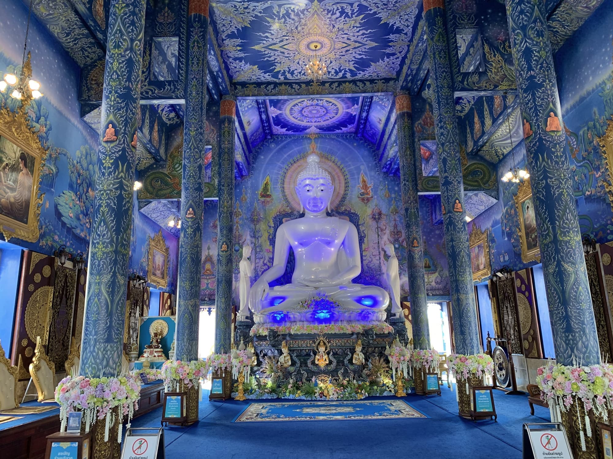 Glowing white Buddha inside the deep blue hall of the Blue Temple