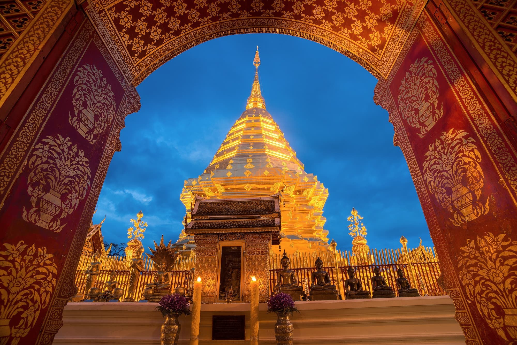 The golden chedi of Wat Phra That Doi Suthep framed by a carved red archway